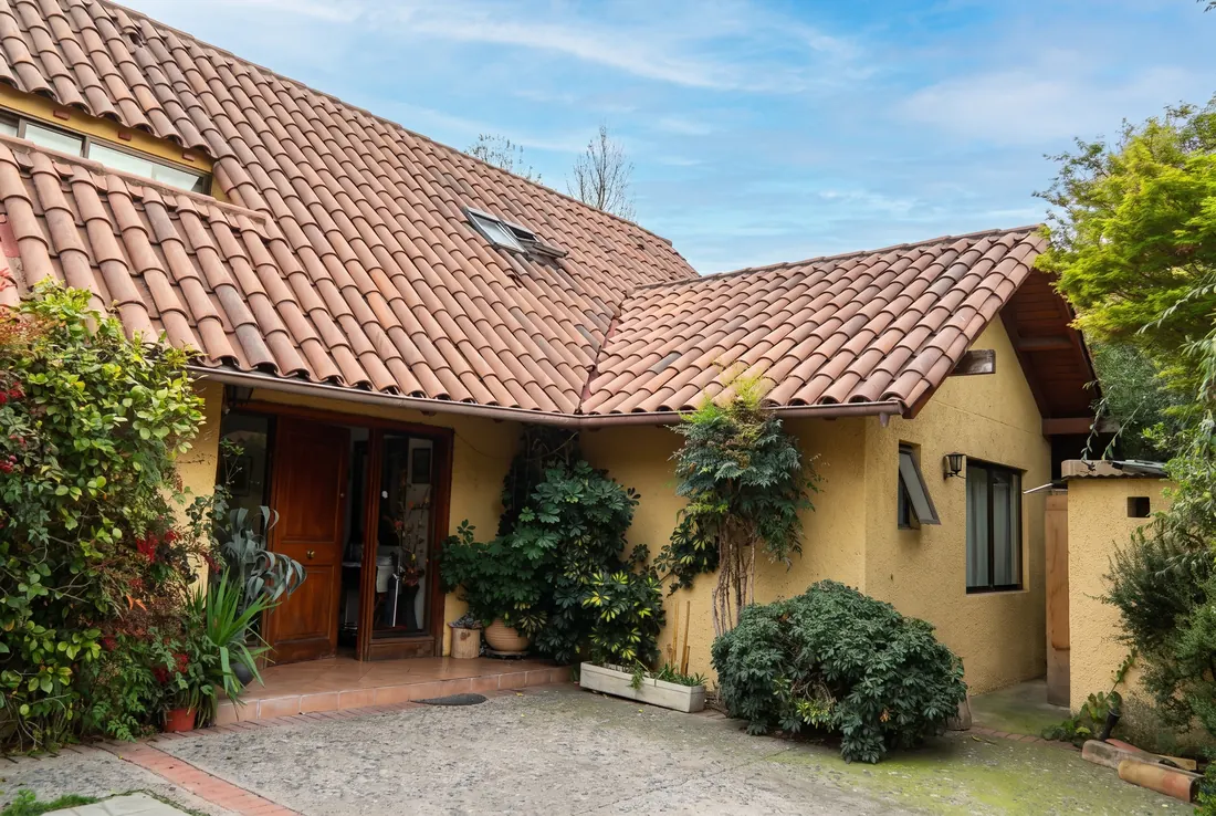 Fachada de la Casa 1: techo de teja, muros ocre y puerta de madera con jardín en la entrada