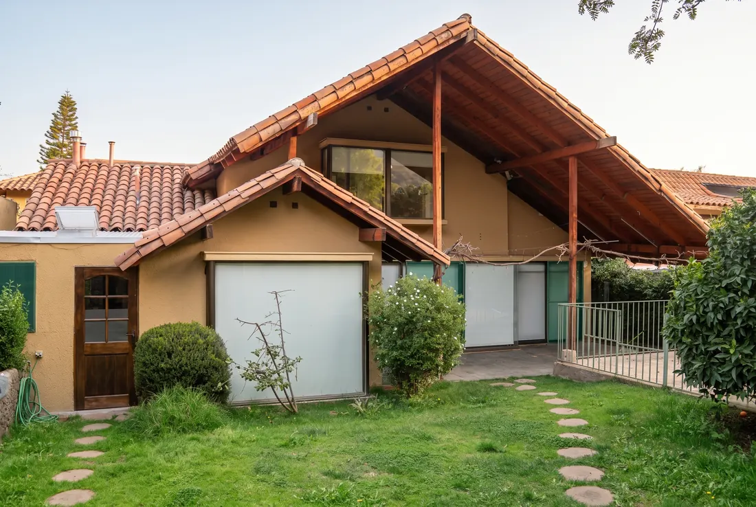 Fachada de la Casa 2 hacia el jardín: techo de teja con estructura de madera a la vista y piscina cercada